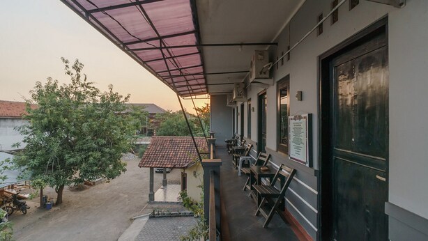 Un balcón exterior con zona cubierta, mobiliario y vistas de los edificios y árboles circundantes.