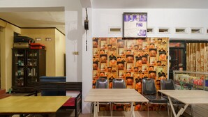 Interior de restaurante con mesas y sillas, una pared decorada con carteles y una barra con varios artículos.