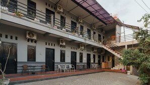 Un edificio de dos pisos con varios balcones, unidades de aire acondicionado y mobiliario exterior.