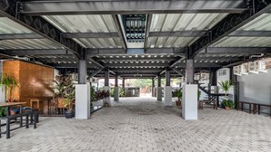 An open-plan area with a brick floor, metal beams, and potted plants.
