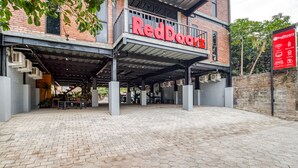 A RedDoorz building with a covered entrance, hexagonal paving, and a brick facade.