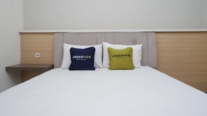 A bed with two pillows, one blue and one green, both labeled "URBANVIEW HOTELS". - Urbanview Hotel Double Tree Purwokerto (Purwokerto)