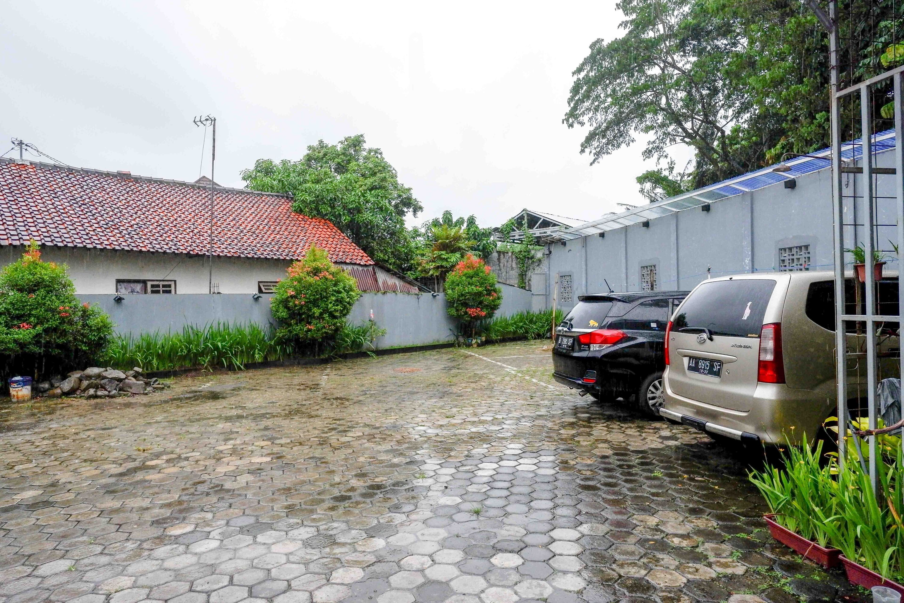 Un patio con piso empedrado, un edificio con techo de tejas y coches estacionados.