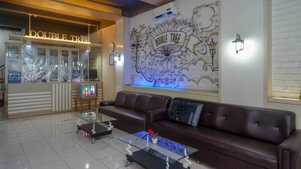 A modern lobby with a leather sofa, glass coffee table, and a wall mural. - Urbanview Hotel Double Tree Purwokerto (Purwokerto)