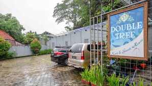 A courtyard with a paved ground, a parked van, and a sign for "DOUBLE TREE Kost & Guest House". - Urbanview Hotel Double Tree Purwokerto (Purwokerto)