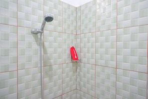 A shower with a handheld showerhead and a red soap dispenser mounted on the wall. - RedDoorz near Taman Makam Pahlawan Tatura (Palu)