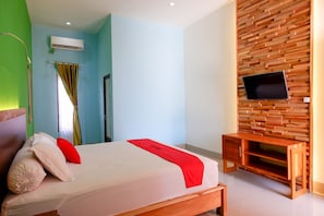 A bedroom with a bed, a TV mounted on a wooden wall, and a bedside table.
