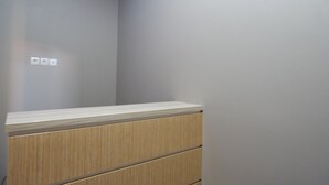 Quarto com um armário de madeira e parede em tom claro.