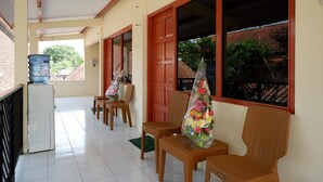 A covered outdoor seating area with wicker chairs, a water dispenser, and a view of the neighborhood.