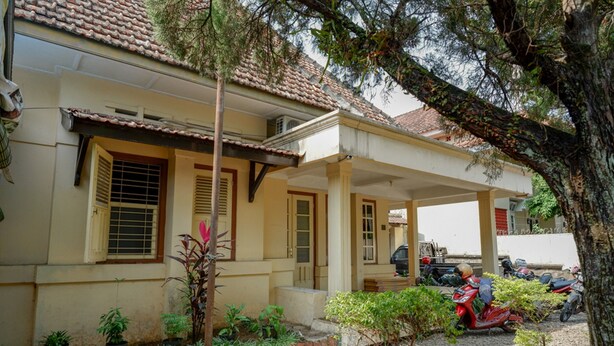 A building with a tiled roof, a covered porch, and several potted plants.