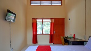 A hotel room with a bed, a desk, a television, and a window with curtains.