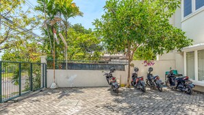 A paved outdoor area with a row of motorcycles parked against a wall. - RedDoorz near UNTAG Surabaya (Surabaya)