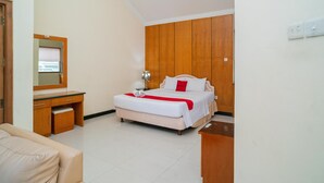 A hotel room with a bed, a wooden wardrobe, a desk, and a chair. - RedDoorz near Rumah Sakit Baptis Kediri (Kediri)