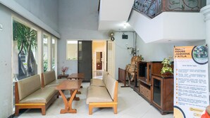 A hotel lobby with a reception desk, seating area, and a staircase. - RedDoorz near Rumah Sakit Baptis Kediri (Kediri)