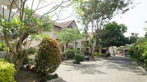 A paved courtyard with potted plants and trees, surrounded by buildings with a traditional architectural style. - RedDoorz near Rumah Sakit Baptis Kediri (Kediri)