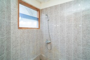 Un baño con ducha, paredes de azulejos y ventana.