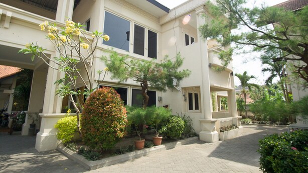 A two-story building with a courtyard, potted plants, and a small tree. - RedDoorz near Rumah Sakit Baptis Kediri (Kediri)