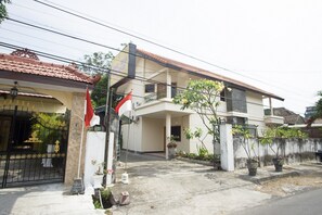 Una casa de dos pisos con un balcón, una bandera y plantas en macetas.