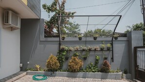 A courtyard with a grey wall, potted plants, and a hose on the ground. - RedDoorz Syariah near Pahoman Stadium Lampung (Bandar Lampung)