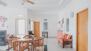 A spacious living area with a dining table and chairs, a sofa, and a ceiling fan. - RedDoorz Syariah near Pahoman Stadium Lampung (Bandar Lampung)