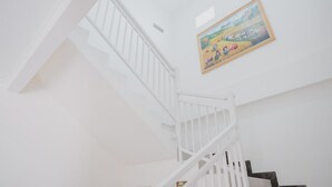 A white staircase with a painting of a landscape on the wall. - RedDoorz Syariah near Pahoman Stadium Lampung (Bandar Lampung)