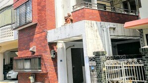 A multi-story building with a red brick facade, balconies, and a gated entrance. - Naha Tomarin House (Naha)