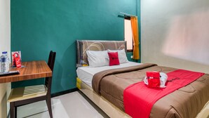 A hotel room with a bed, a wooden desk, and a chair. - RedDoorz Syariah near Airlangga University Campus B (Surabaya)