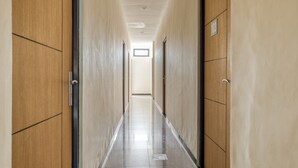 A long, narrow hallway with wooden doors on both sides and a tiled floor. - RedDoorz Syariah near Airlangga University Campus B (Surabaya)