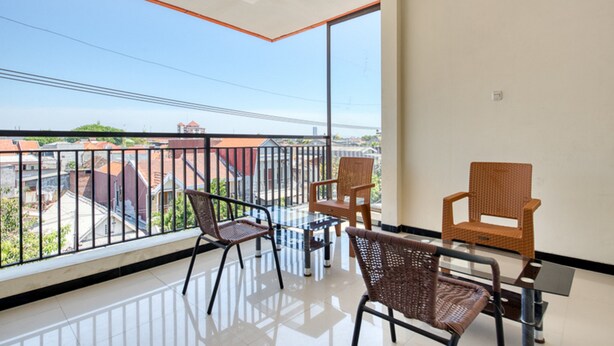 A balcony with a glass table and chairs, offering a view of buildings and a clear sky. - RedDoorz Syariah near Airlangga University Campus B (Surabaya)