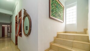 A hallway with a staircase, a mirror, and a framed painting on the wall.