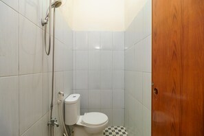 A small, tiled bathroom with a toilet, shower, and a wooden door. - RedDoorz Syariah @ Jalan Dr Mansyur Medan (Medan)