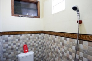 A bathroom with a toilet, a shower, and a window. - RedDoorz near Desa Wisata Tambi Dieng (Kejajar)