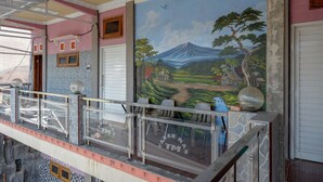 Una habitación con un mural de paisaje, un balcón con barandilla y suelo de baldosas.