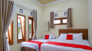 Habitación de hotel con dos camas, cada una con ropa blanca y detalles rojos, un cabecero de madera y una ventana con cortinas.