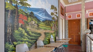 Una habitación con un mural de un paisaje, una puerta de madera y un suelo de baldosas.