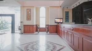 A spacious lobby with a polished floor, a reception desk, and decorative wall panels. - RedDoorz Premium @ Jalan Pal 10 Jambi (Jambi)