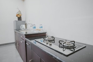 A kitchen with a gas stove, a coffee maker, and a water dispenser.
