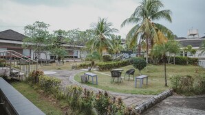 A courtyard with palm trees, a staircase, and outdoor seating. - RedDoorz Premium @ Jalan Pal 10 Jambi (Jambi)