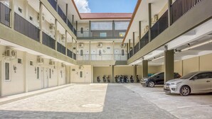 Un aparcamiento de varios niveles con un espacio central abierto, varias motocicletas y algunos coches estacionados en la planta baja.