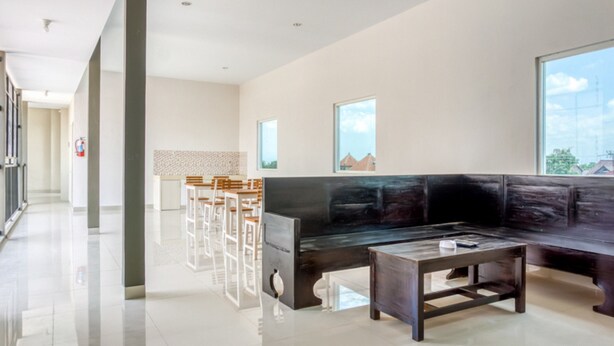 Un interior moderno con un sofá negro, una mesa de centro de madera y sillas blancas.
