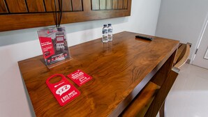 Un mostrador de recepción de madera con un letrero de Red Door, dos botellas de agua, un control remoto y un cartel de 'No molestar'.
