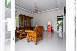 Een ruime woonkamer met een houten bank, een glazen salontafel en een houten kast.