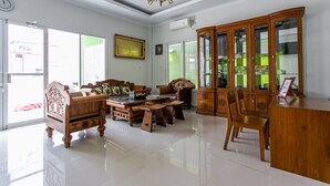 Un salón amplio con un conjunto de sofá de madera, una mesa de centro y un aparador de madera.