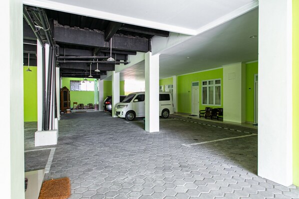 A parking garage with hexagonal patterned flooring, white pillars, and green walls. - RedDoorz Near Universitas Muhammadiyah Yogyakarta (Kasihan)