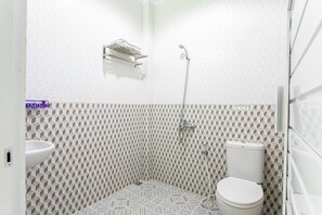 A small, modern bathroom with a toilet, a sink, and a shower. - RedDoorz Near Universitas Muhammadiyah Yogyakarta (Kasihan)