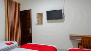 A hotel room with two beds, a wooden chair, a desk, and a television on the wall. - RedDoorz near Living Plaza Purwokerto (Purwokerto)