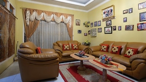 A living room with a brown leather sofa set, a coffee table, and a red and white patterned rug.