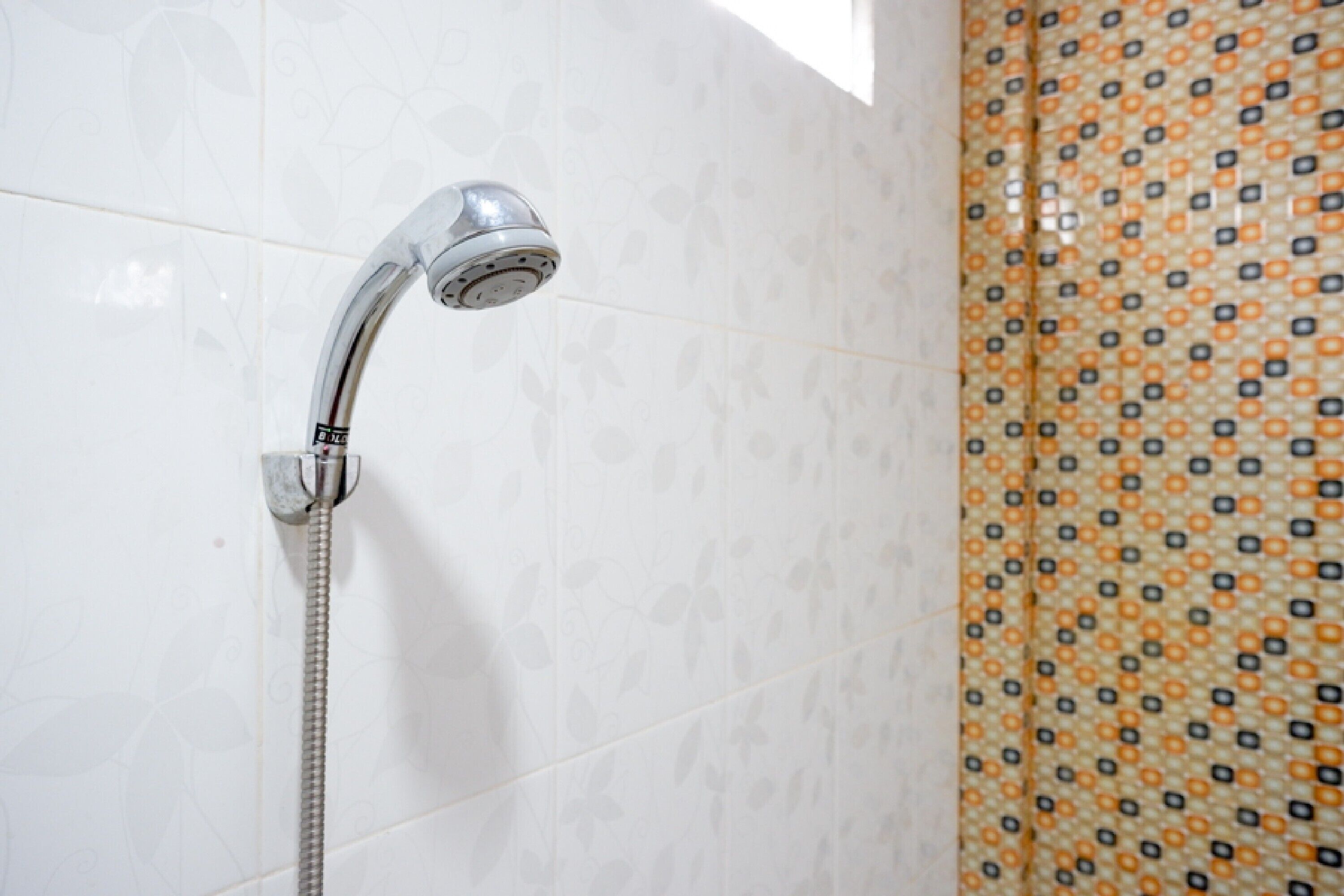 A bathroom with a shower, tiled walls, and a patterned shower curtain.