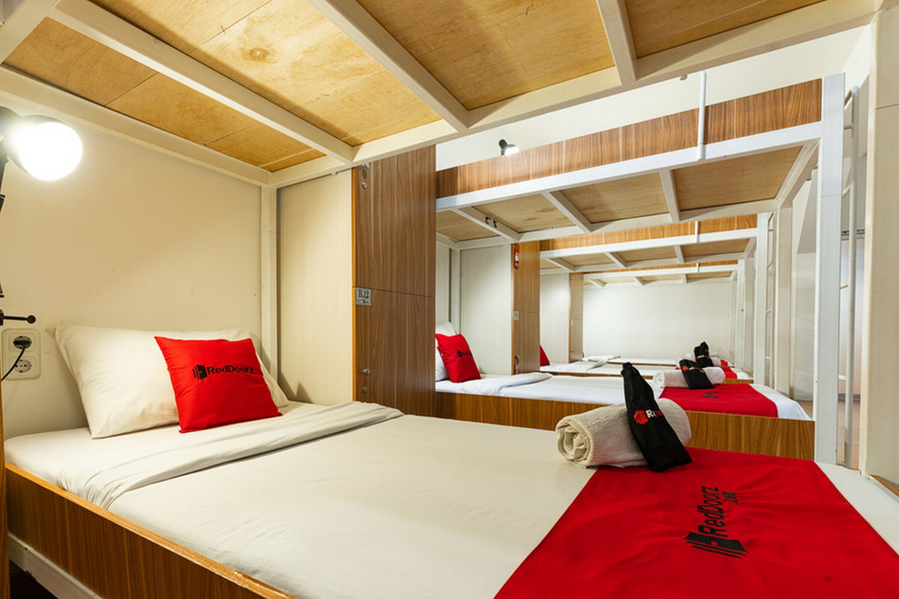 A hotel room with two beds, wooden headboards, a large mirror, and a RedDoor logo on the beds.