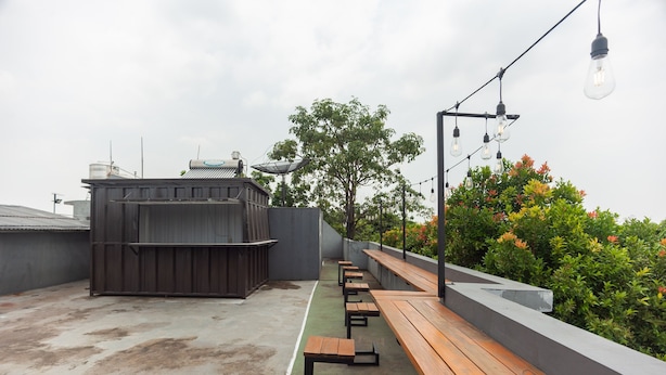 Terraço no telhado com bancos de madeira e um pequeno bar.